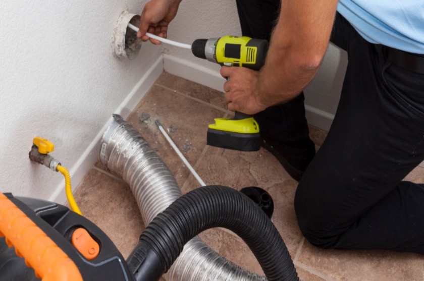 Person using a drill to clean a vent.